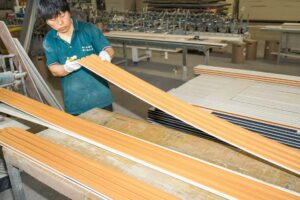 Factory worker inspecting WPC wall panel in production workshop
