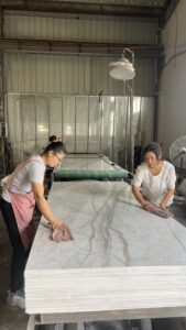 Workers inspect UV coated PVC marble sheet in factory workshop