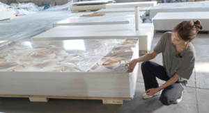 Worker measuring thickness of PVC marble sheet during factory quality inspection